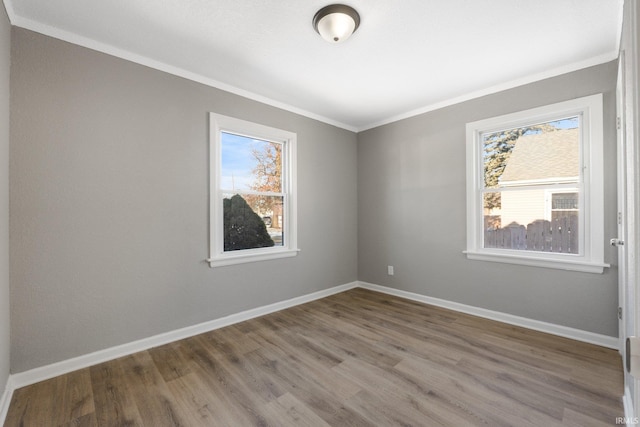 unfurnished room featuring hardwood / wood-style floors, ornamental molding, and a healthy amount of sunlight