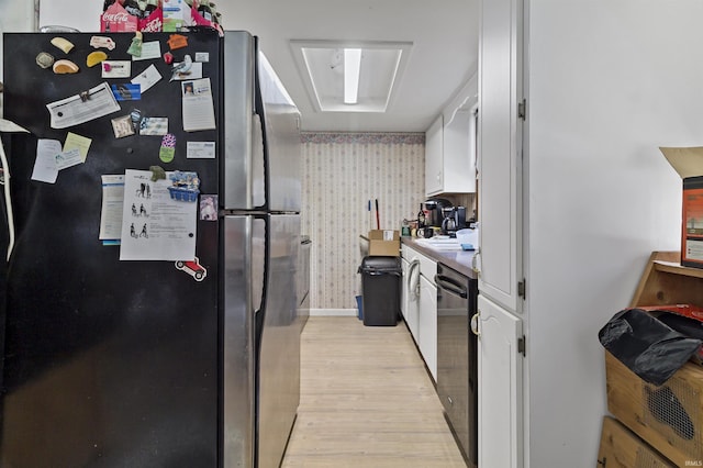 kitchen featuring light wood finished floors, wallpapered walls, dishwasher, freestanding refrigerator, and white cabinetry