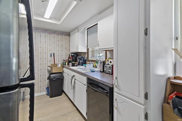 kitchen featuring black dishwasher, white cabinetry, freestanding refrigerator, light wood-style floors, and wallpapered walls