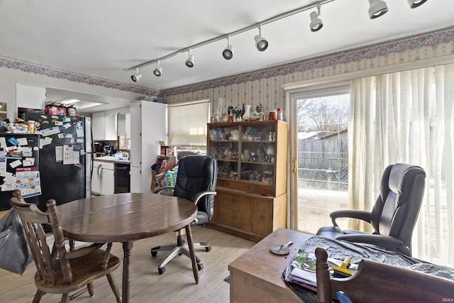 home office with light wood-style flooring and wallpapered walls