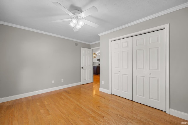 unfurnished bedroom featuring ceiling fan, ornamental molding, light hardwood / wood-style flooring, and a closet