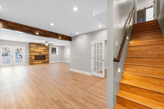 interior space featuring french doors, ceiling fan, light hardwood / wood-style flooring, beamed ceiling, and a fireplace