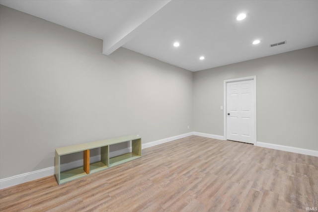 unfurnished room with beamed ceiling and light hardwood / wood-style floors