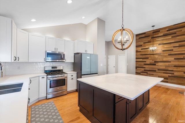 kitchen with pendant lighting, a center island, an inviting chandelier, appliances with stainless steel finishes, and white cabinetry