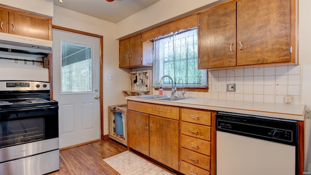 kitchen with tasteful backsplash, white dishwasher, sink, range, and light hardwood / wood-style floors