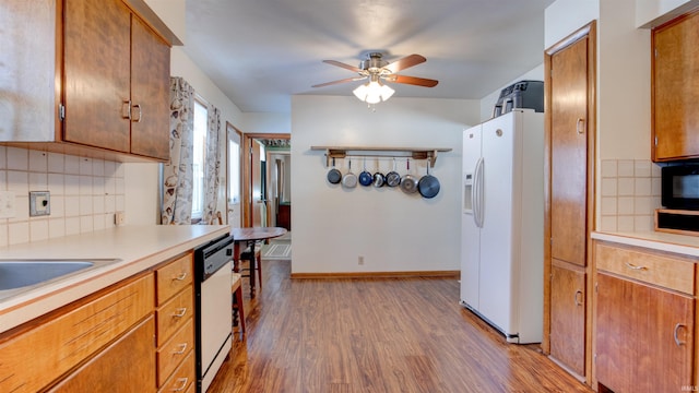 kitchen with decorative backsplash, ceiling fan, white appliances, and light wood-type flooring