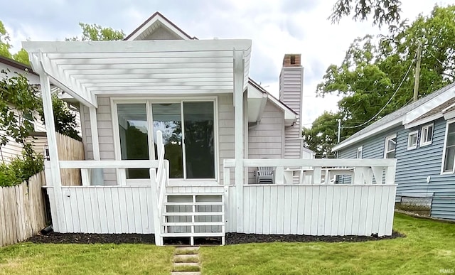 rear view of house featuring a pergola and a yard