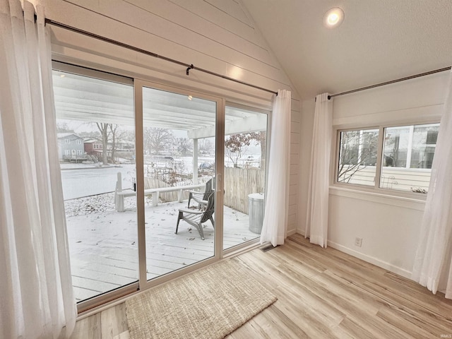 doorway to outside featuring light hardwood / wood-style floors and lofted ceiling