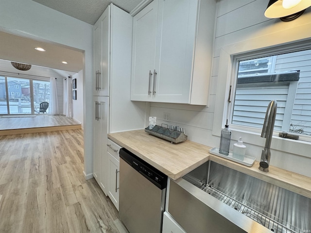 kitchen featuring stainless steel dishwasher, white cabinets, sink, and light hardwood / wood-style flooring