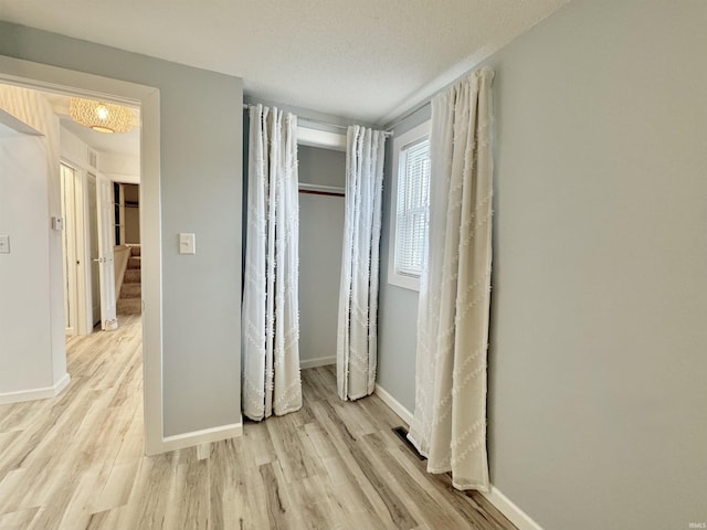 unfurnished bedroom featuring light wood-type flooring, a textured ceiling, and a closet