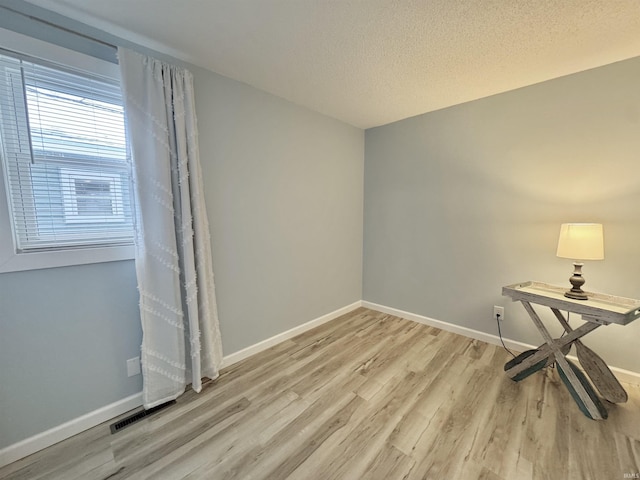 spare room featuring a textured ceiling and light wood-type flooring