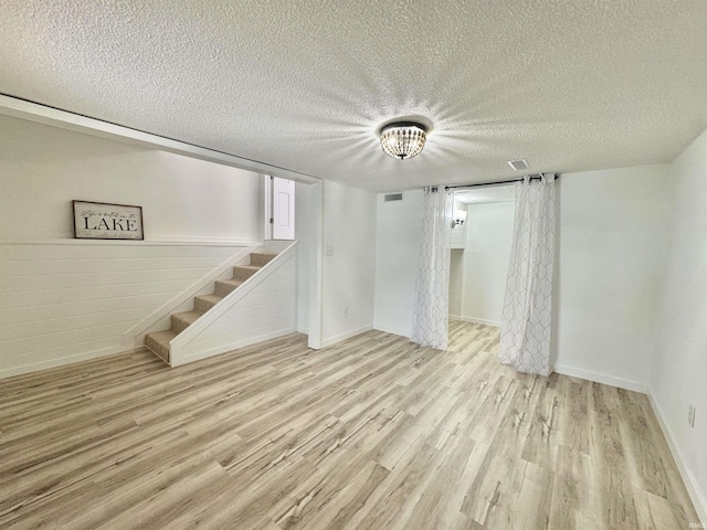 basement with light hardwood / wood-style floors and a textured ceiling