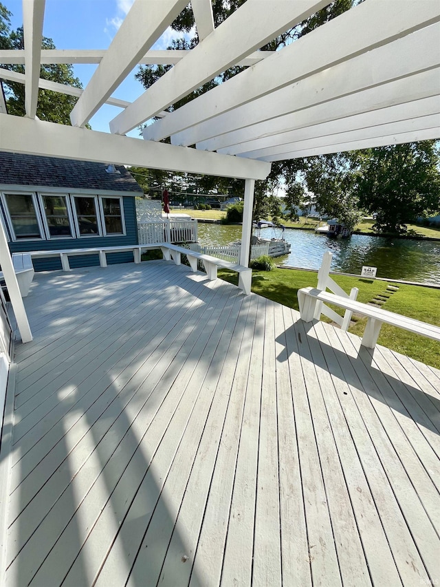 deck featuring a water view, a pergola, and a yard