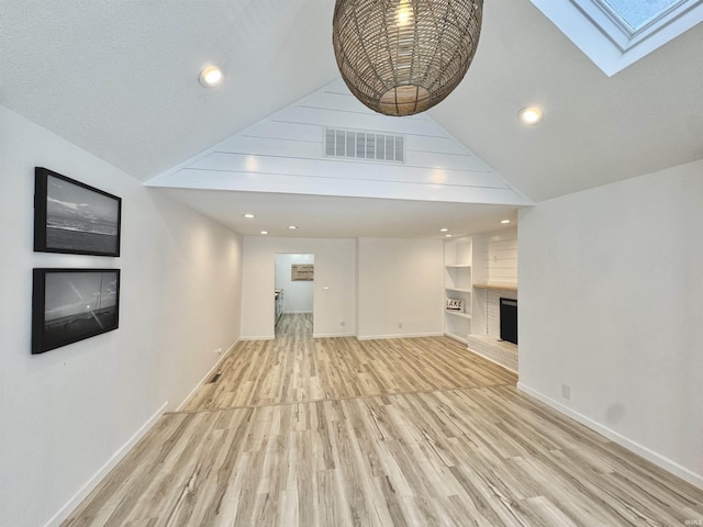 unfurnished living room with built in shelves, light wood-type flooring, a fireplace, and high vaulted ceiling