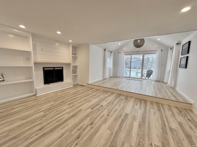 unfurnished living room with a fireplace, light hardwood / wood-style flooring, vaulted ceiling, and built in features