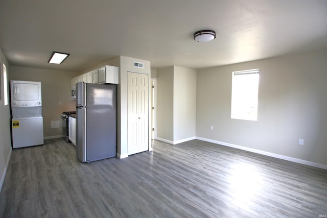 kitchen featuring dark hardwood / wood-style floors, white cabinetry, appliances with stainless steel finishes, and stacked washer and clothes dryer