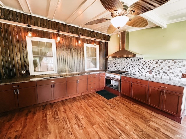 kitchen with ceiling fan, wall chimney range hood, backsplash, crown molding, and light hardwood / wood-style floors