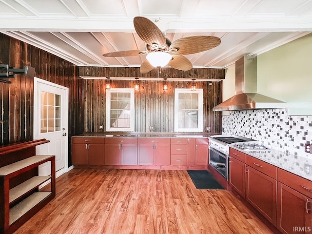 kitchen with light hardwood / wood-style flooring, ceiling fan, wall chimney exhaust hood, and crown molding