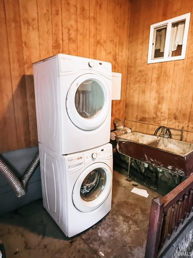 laundry room featuring stacked washer and clothes dryer and wood walls