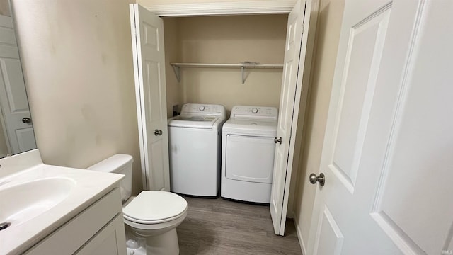 bathroom featuring washing machine and dryer, hardwood / wood-style floors, vanity, and toilet