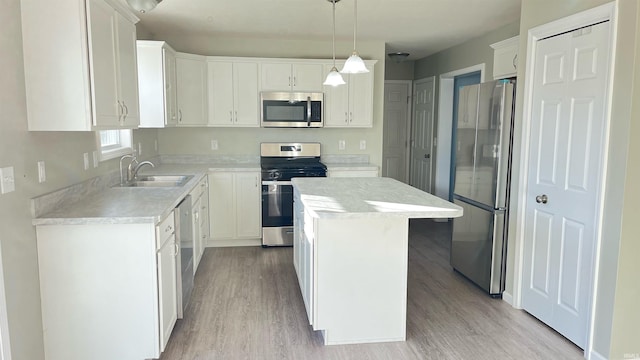 kitchen featuring sink, hanging light fixtures, stainless steel appliances, a kitchen island, and white cabinets