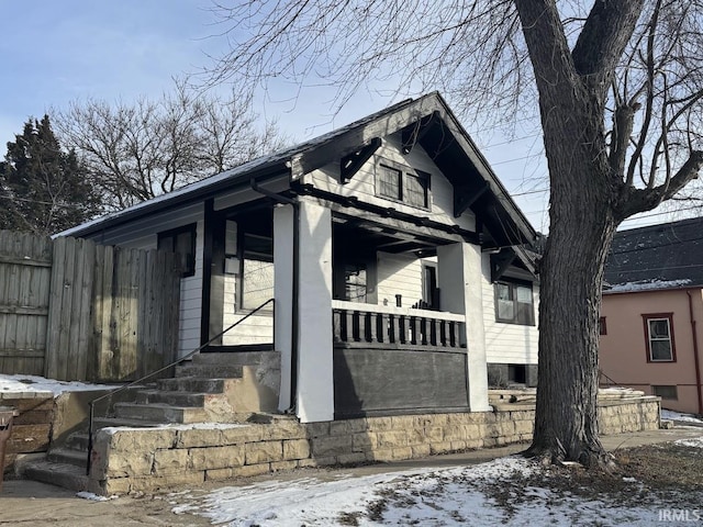 snow covered property with covered porch