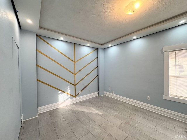 unfurnished room featuring a textured ceiling and a tray ceiling