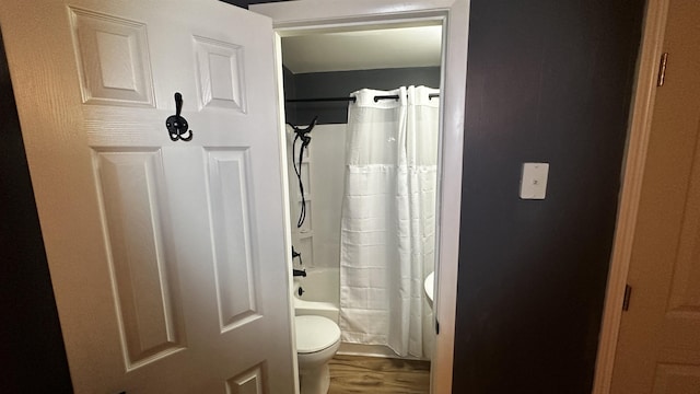 bathroom with toilet, hardwood / wood-style flooring, and shower / tub combo with curtain