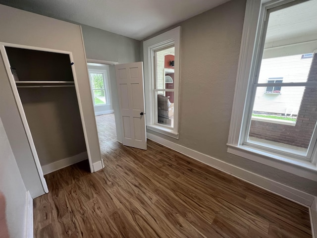 unfurnished bedroom with dark hardwood / wood-style floors and a closet