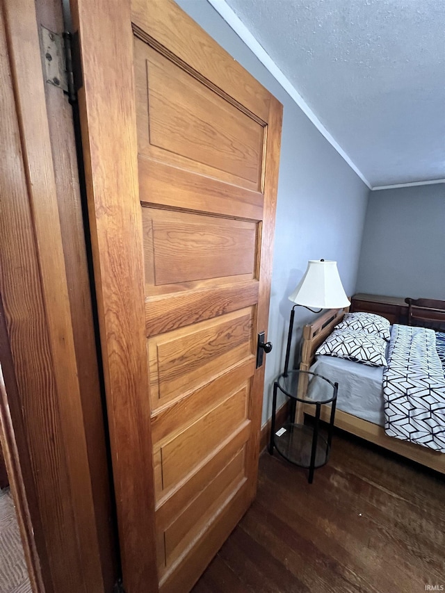 bedroom featuring a textured ceiling, dark hardwood / wood-style flooring, and vaulted ceiling