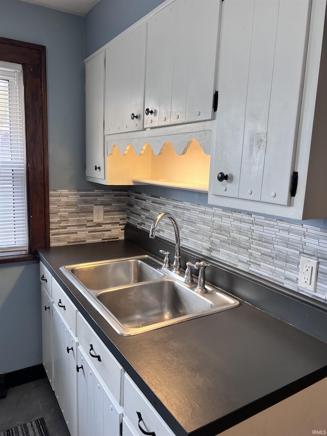 kitchen with backsplash, white cabinetry, sink, and dark tile patterned flooring