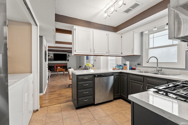 kitchen with washer and clothes dryer, dishwasher, white cabinets, sink, and light tile patterned floors