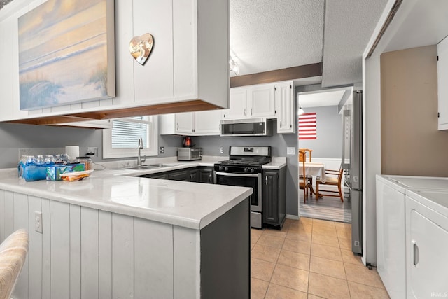 kitchen featuring white cabinetry, sink, stainless steel appliances, washing machine and dryer, and a textured ceiling