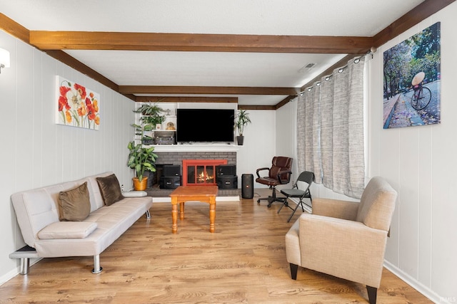 living room with a fireplace, beamed ceiling, and light hardwood / wood-style floors