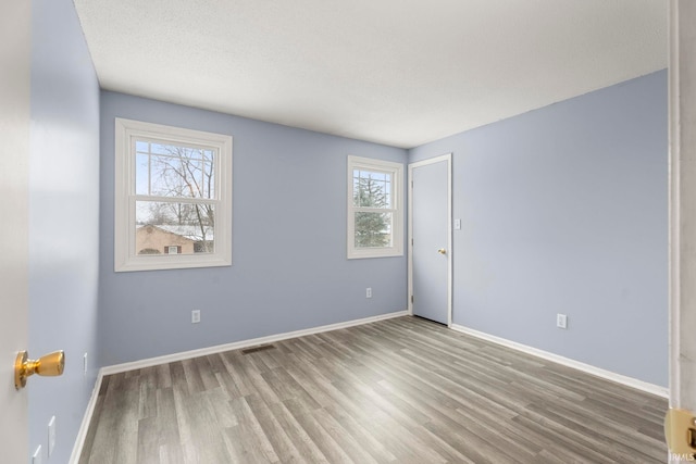 empty room featuring plenty of natural light and hardwood / wood-style floors