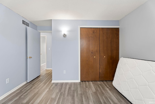 unfurnished bedroom featuring light hardwood / wood-style floors and a closet