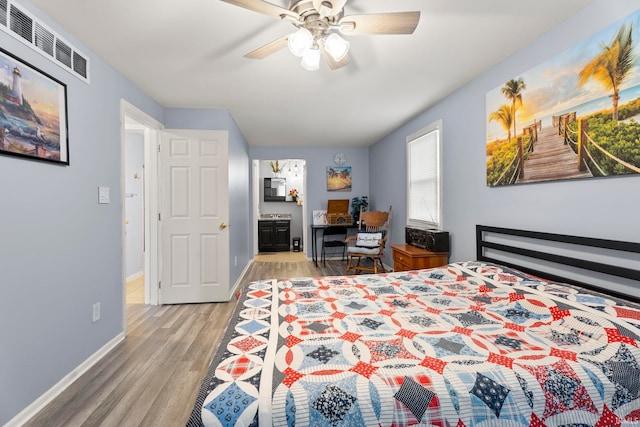 bedroom featuring ceiling fan, light hardwood / wood-style floors, and ensuite bath