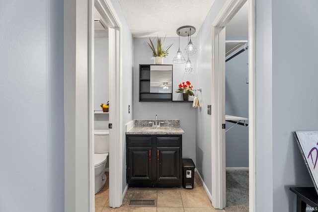 bathroom with tile patterned flooring, vanity, toilet, and a textured ceiling