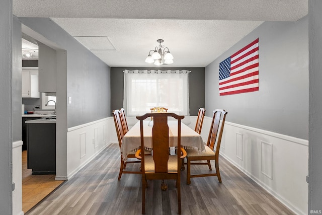 dining area featuring a chandelier, hardwood / wood-style floors, a textured ceiling, and sink