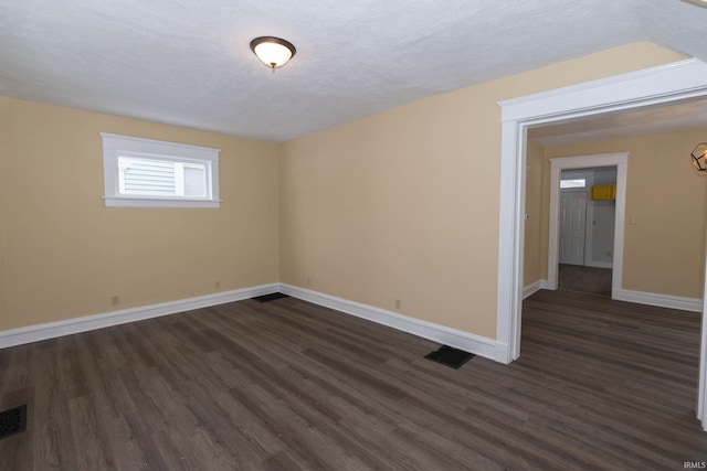 unfurnished room with a textured ceiling and dark hardwood / wood-style floors