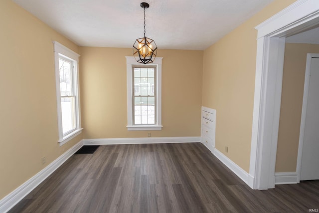 unfurnished room featuring an inviting chandelier and dark wood-type flooring