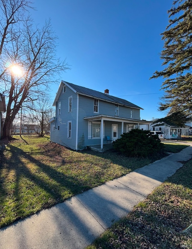 view of side of home featuring a lawn and covered porch