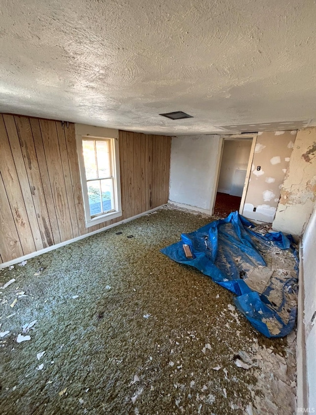 interior space with wood walls and a textured ceiling