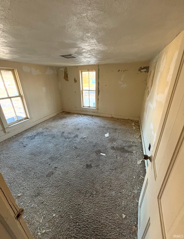 carpeted spare room featuring a textured ceiling