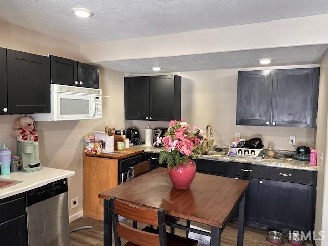 kitchen with a textured ceiling, dishwasher, wood-type flooring, and sink