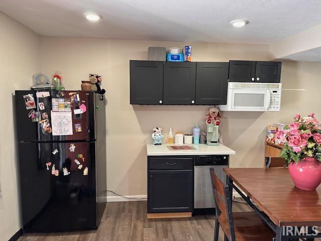 kitchen with dishwasher, dark hardwood / wood-style flooring, and black fridge