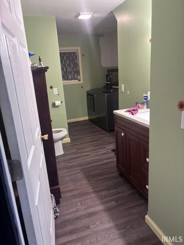 bathroom with toilet, vanity, washer and dryer, and wood-type flooring