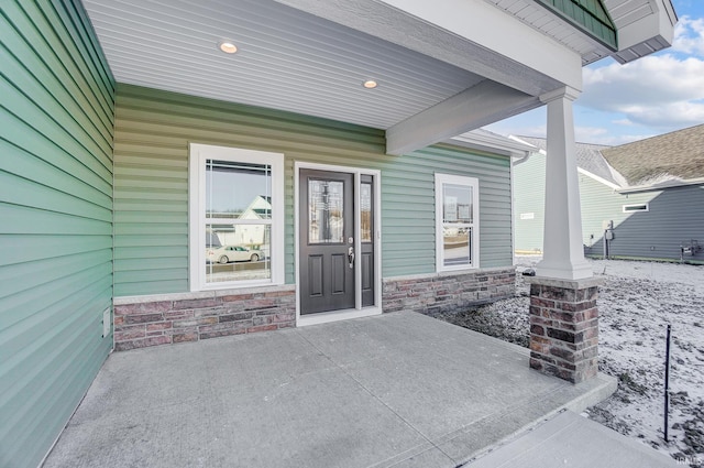 snow covered property entrance featuring covered porch