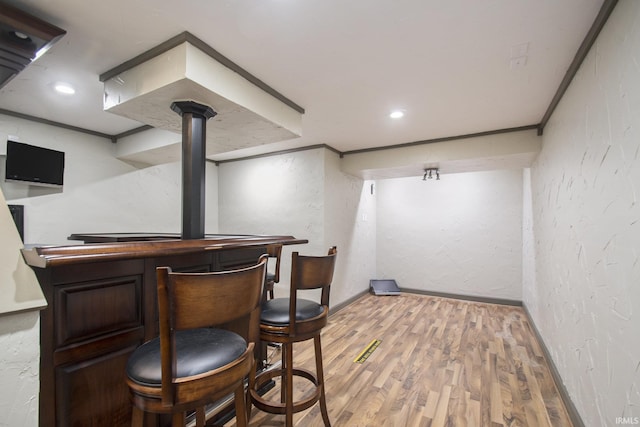 bar featuring dark brown cabinets, light hardwood / wood-style floors, and ornamental molding