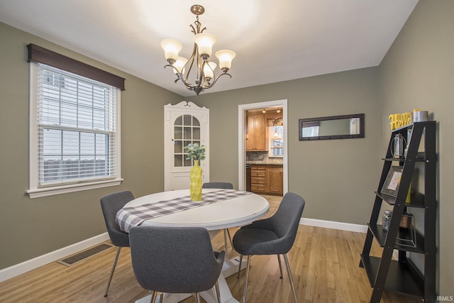 dining area with light hardwood / wood-style floors and a notable chandelier